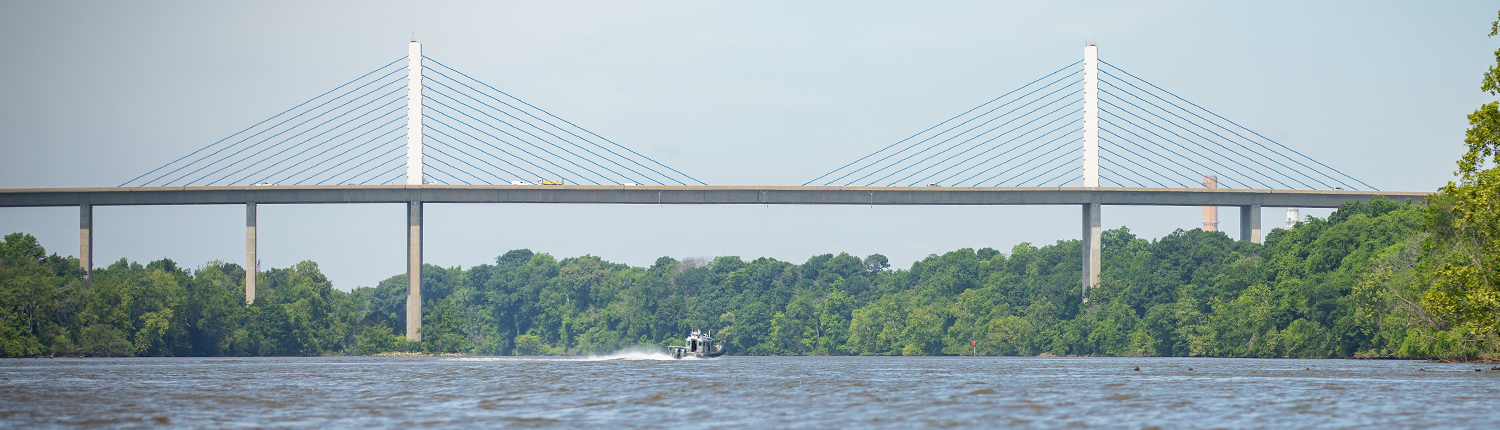 A wide shot of the Henrico Varina-Enon Bridge with the Henrico Police boat in the center of the river underneath the bridge.